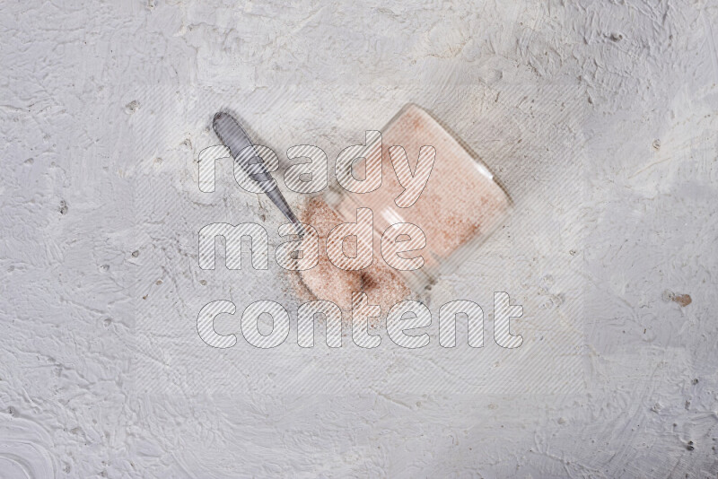 A glass jar full of fine himalayan salt on white background