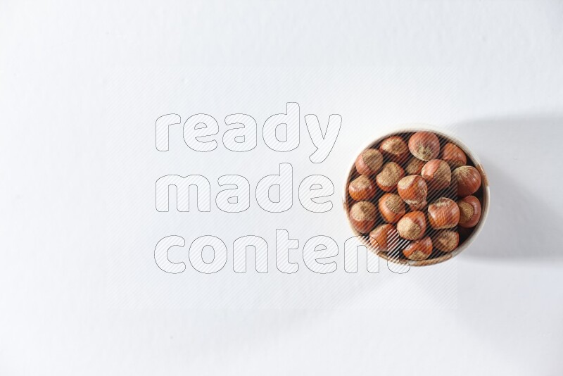 A beige ceramic bowl full of hazelnuts on a white background in different angles