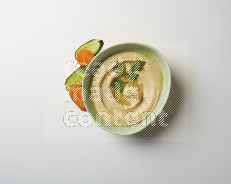 Hummus in a green plate garnished with parsley on a white background