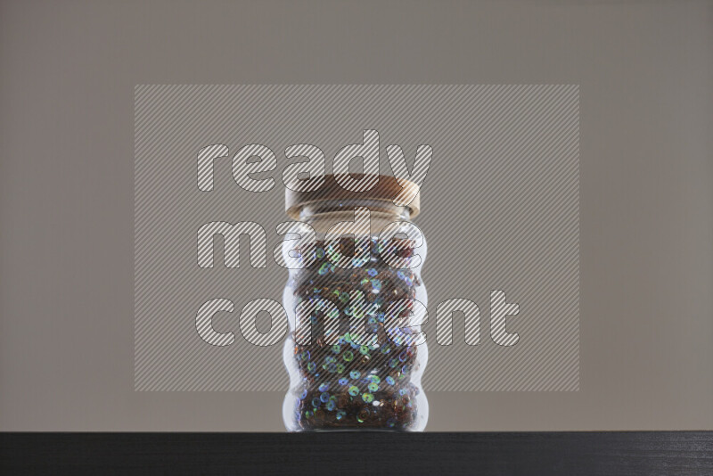 Sequins in a glass jar on black background