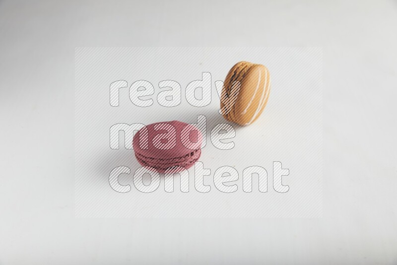 45º Shot of of two assorted Brown Irish Cream, and Red Cherry macarons on white background