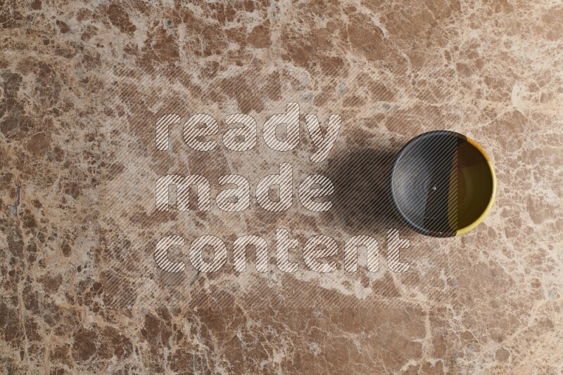 A multicolored pottery bowl on beige marble background