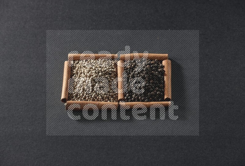 2 squares of cinnamon sticks full of white peppers and black peppers on black flooring