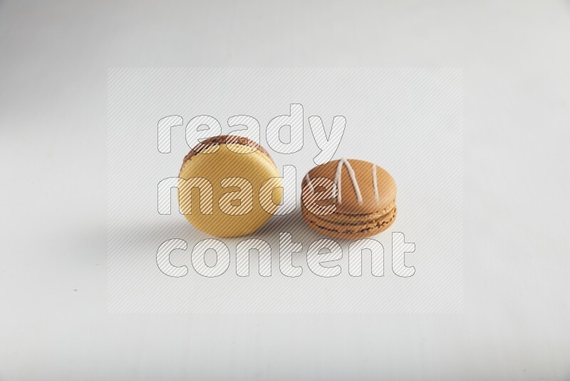 45º Shot of of two assorted Brown Irish Cream, and Yellow, and Brown Chai Latte macarons on white background