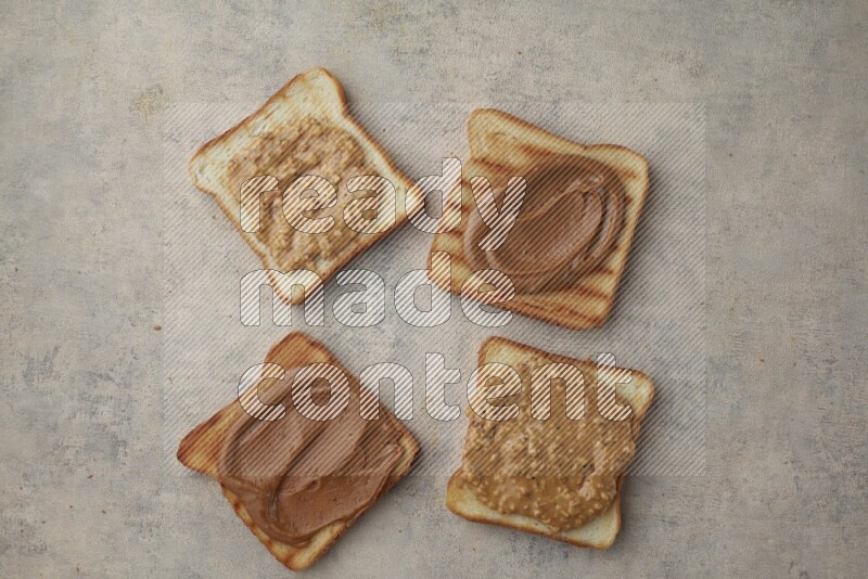 Creamy and crunchy peanut butter on a toasted white toast slices on a light blue textured background