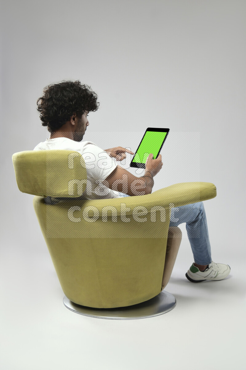 A man wearing casual sitting on a chair showing a tablet screen on white background