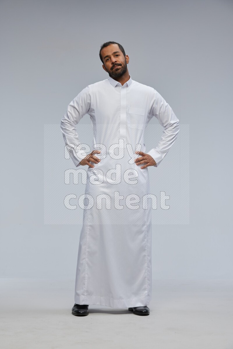 Saudi man Wearing Thob standing interacting with the camera on Gray background