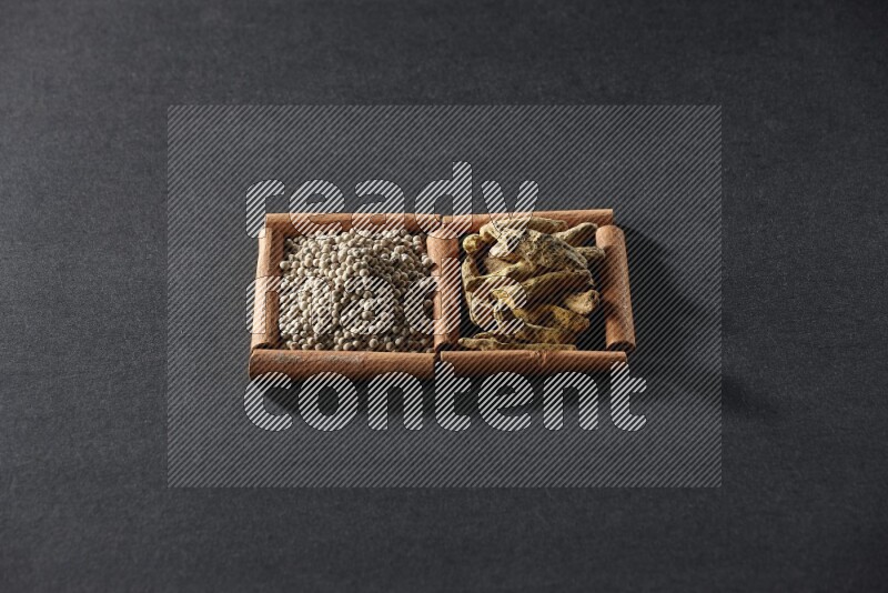 2 squares of cinnamon sticks full of white pepper and turmeric fingers on black flooring