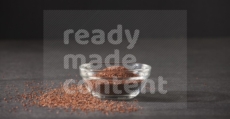 وعاء زجاجي ممتلئ ببذور حب الرشاد محاط بالبذور على أرضية سوداء