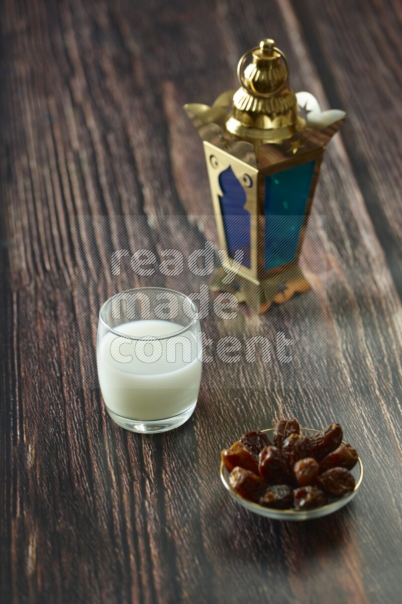 A golden lantern with different drinks, dates, nuts, prayer beads and quran on brown wooden background