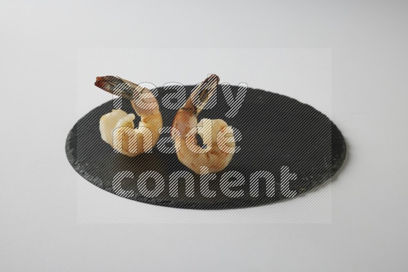 two grilled shrimp  on a black slate direct  on a white back ground
