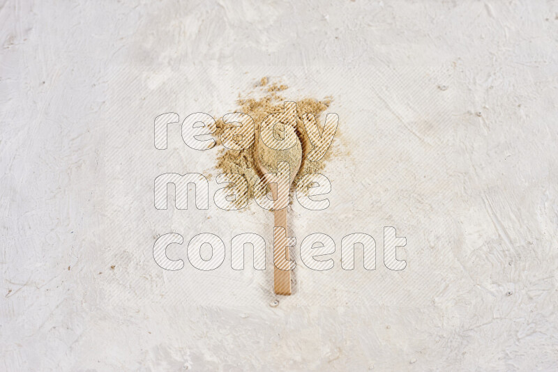A wooden spoon full of ground ginger powder on white background