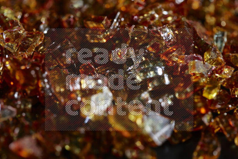 Transparent orange fragments of glass scattered on a black background