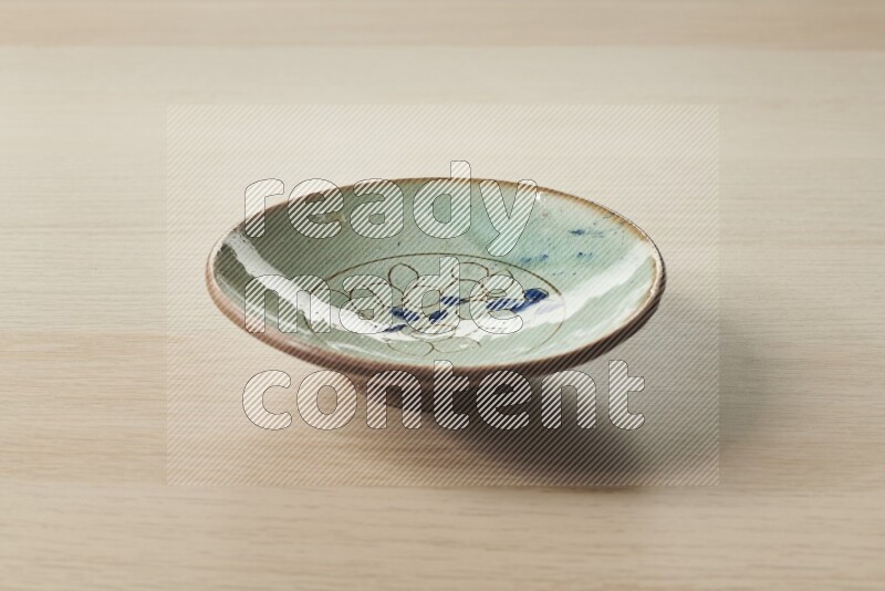 A decorative pottery plate on light wooden background
