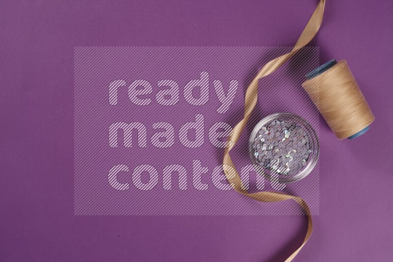 A beige collection of sewing and tailoring tools arranged on a purple background