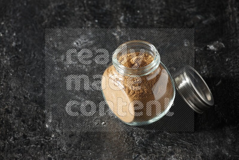 وعاء زجاجي للتوابل ممتلئ ببودرة بهار الفلفل الحلو على خلفية سوداء