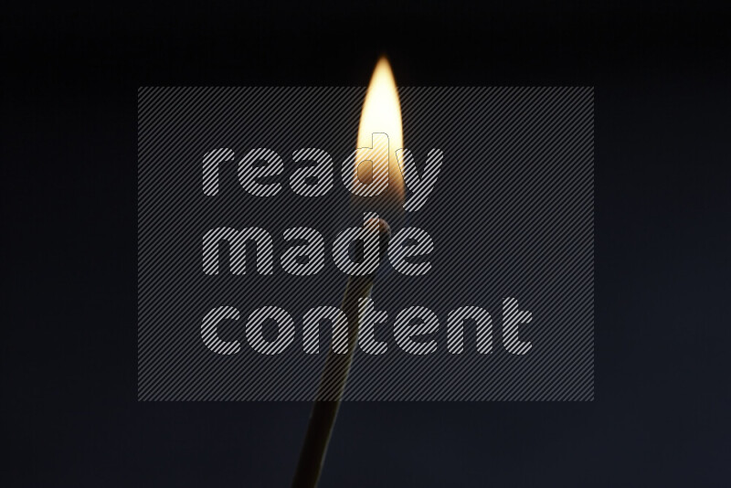 A burning matchstick isolated on dark backdrop