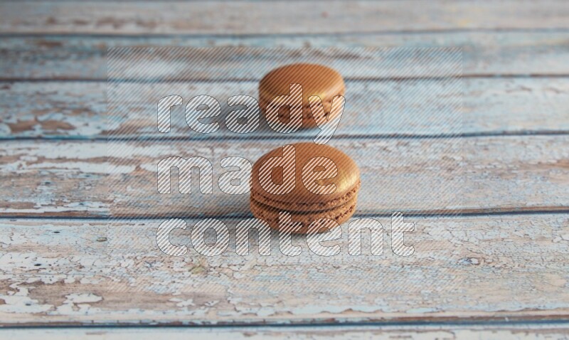 45º Shot of two Brown Coffee macarons on light blue wooden background