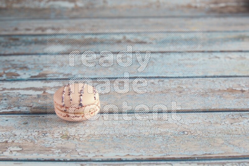 45º Shot of pink orange blossom macaron on light blue wooden background
