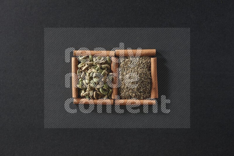 2 squares of cinnamon sticks full of cumin and cardamom on black flooring