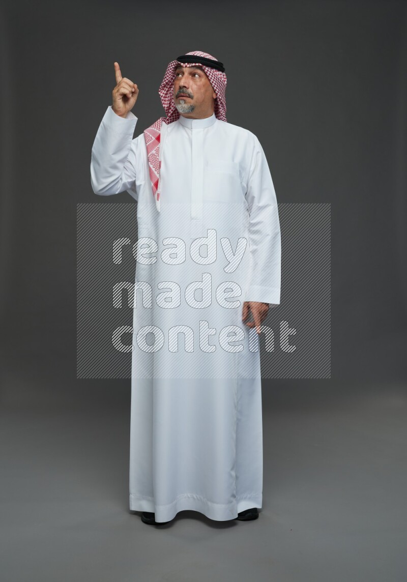 Saudi man with shomag Standing Interacting with the camera on gray background