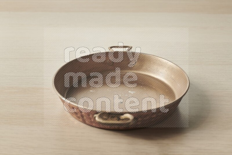 A small copper pan on light wooden background
