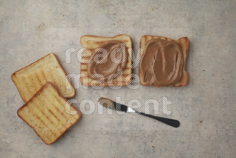 Creamy peanut butter on a toasted white toast and toasted white toast slices on a light blue textured background
