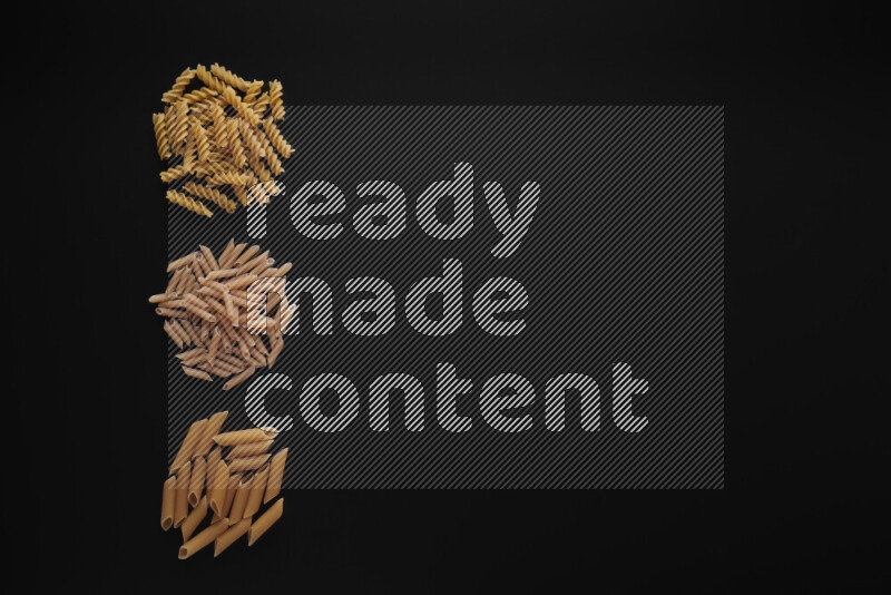 Different pasta types in 3 bunches on black background