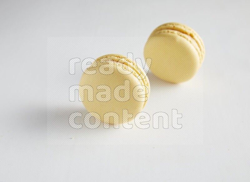 45º Shot of two Yellow Vanilla macarons on white background