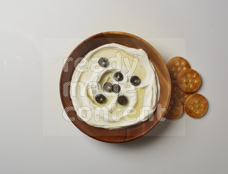 Lebnah garnished with sliced olives in a wooden plate on a white background
