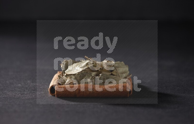 A single square of cinnamon sticks full of laurel bay on black flooring