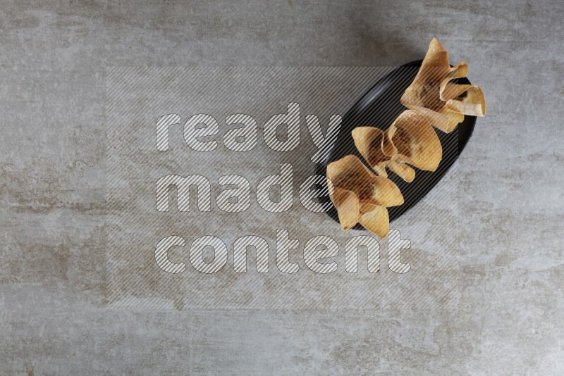wonton cups on oval black ceramic plate on grey textured counter top