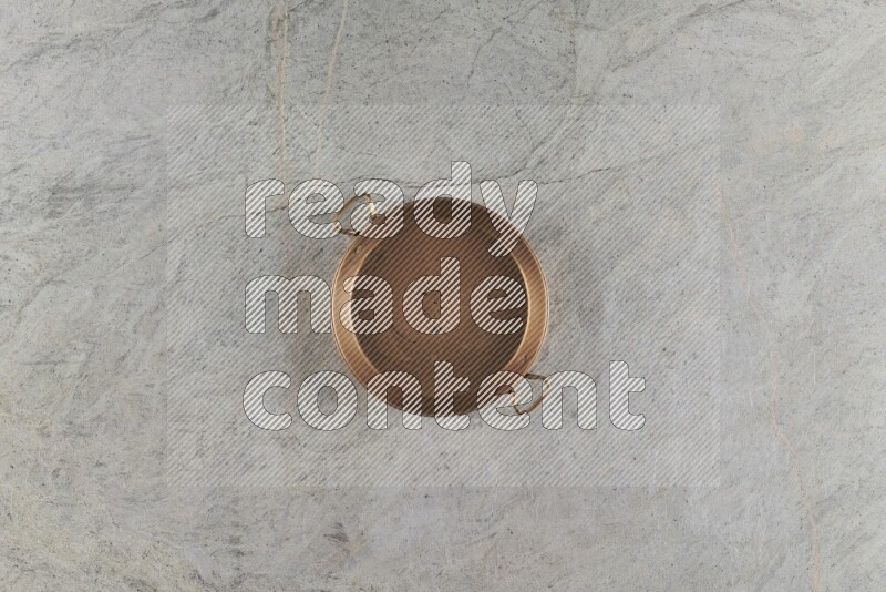 A small copper pan on grey marble background