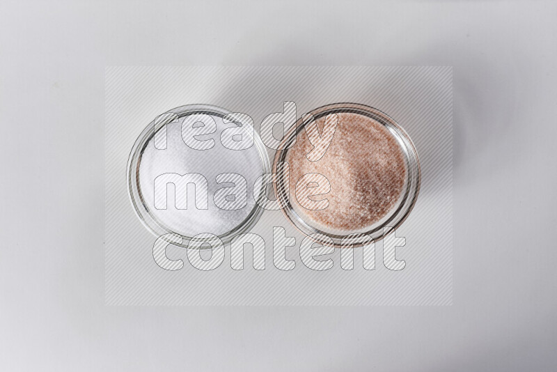 2 glass bowls one is filled with himalayan salt and the other with white salt on white background