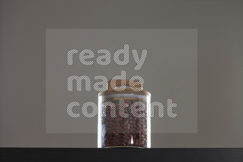 Red kidney beans in a glass jar on black background