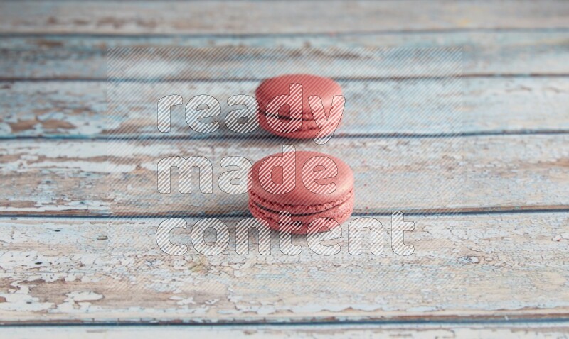 45º Shot of two Pink Raspberry macarons on light blue wooden background