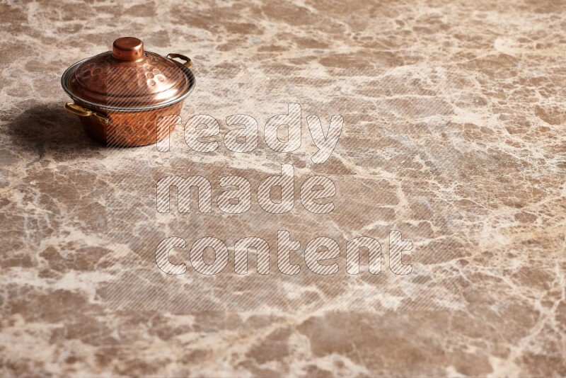 A small copper pot on beige marble background