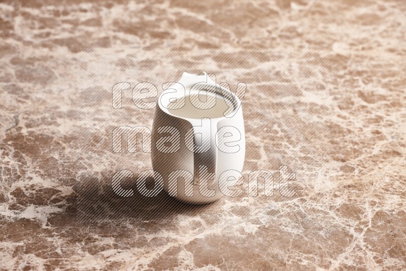 A ceramic milk jug on beige marble background