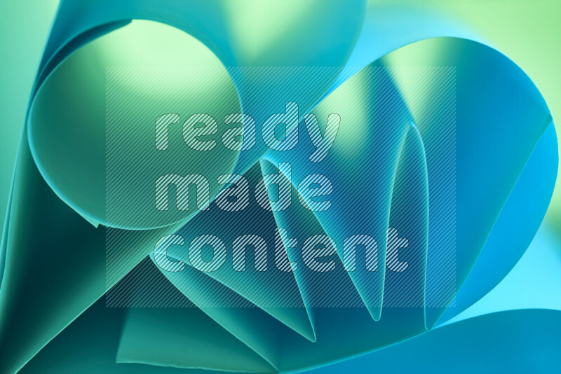 عرض فني لطيات الورق تخلق مزيج من الأشكال الهندسية، مضاءة بإضاءة ناعمة بدرجات اللون الأخضر والأزرق