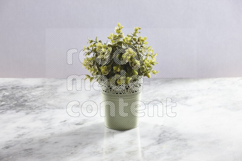 Artificial plant in green decorative pot on grey marble background