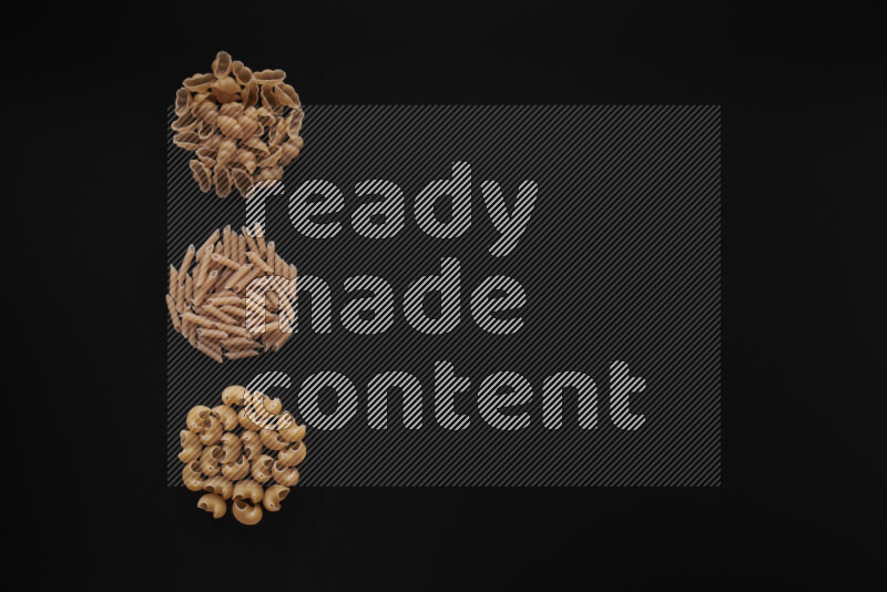 Different pasta types in 3 bunches on black background