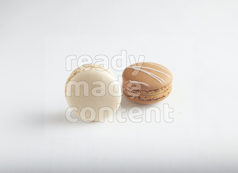 45º Shot of of two assorted Brown Irish Cream, and White Caramel fleur de sel macarons on white background