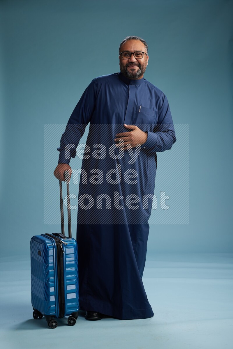 Saudi Man without shimag Standing pulling travel bag on blue background