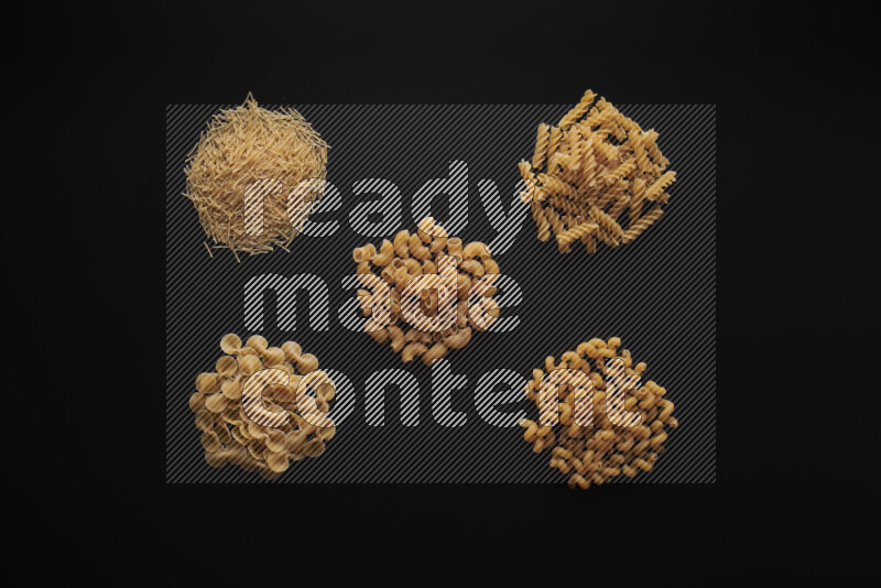 Different pasta types in bunches on black background