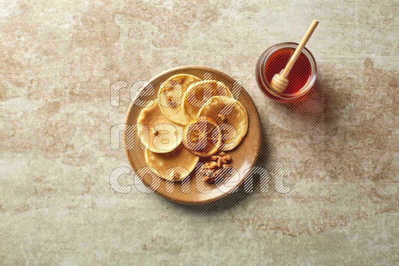 Five stacked dried orange mini pancakes in a brown plate on beige background