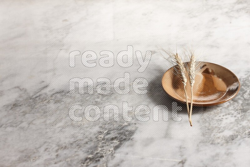 Wheat stalks on multicolored pottery plate on grey marble background
