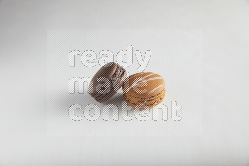 45º Shot of of two assorted Brown Irish Cream, and Brown Dark Chocolate macarons on white background