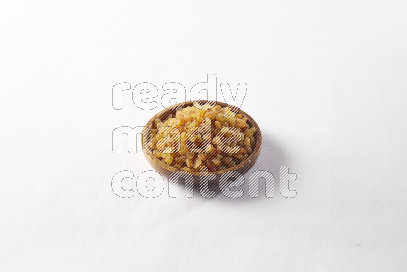 Raisins in a wooden bowl on white background