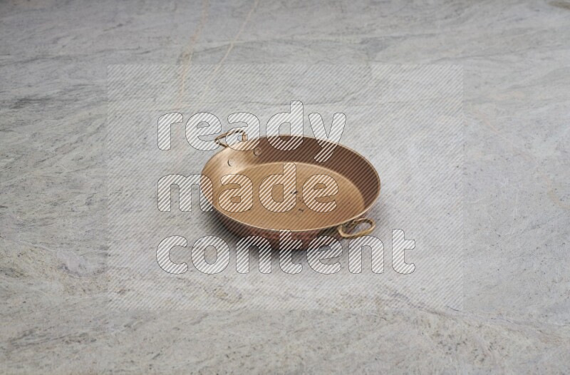A small copper pan on grey marble background