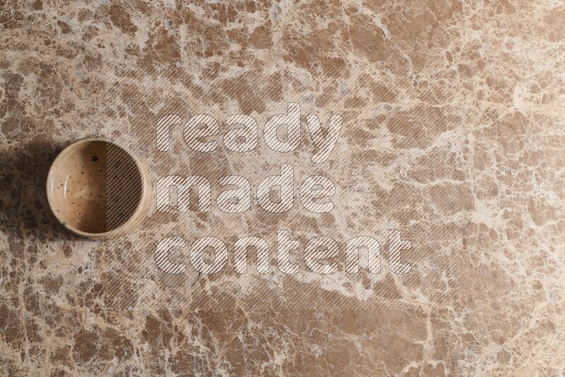 A multicolored pottery bowl on beige marble background